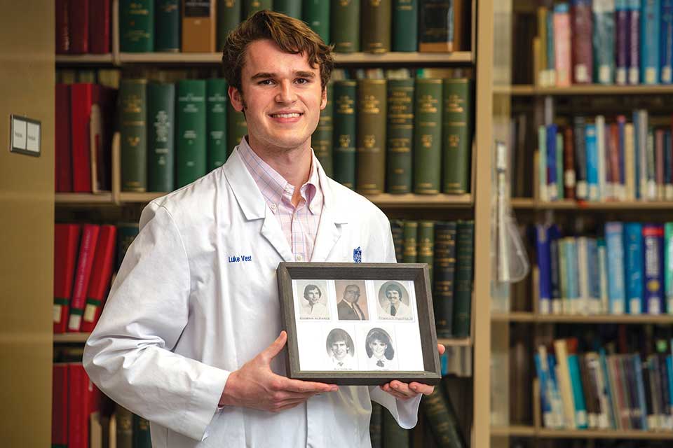 Picture of Luke Vest carrying a picture with of his family that previous attended SLU